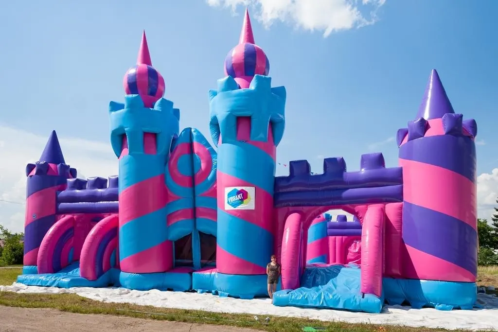 Castillo hinchable gigante con torres rosas y azules al aire libre