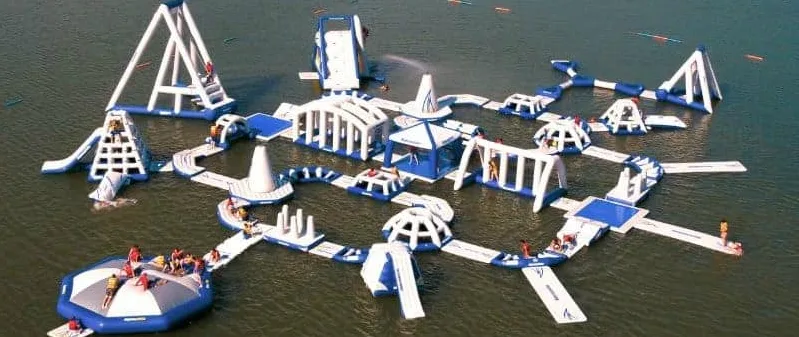Parque acuático hinchable modular flotando en un lago, con toboganes, torres y pasarelas