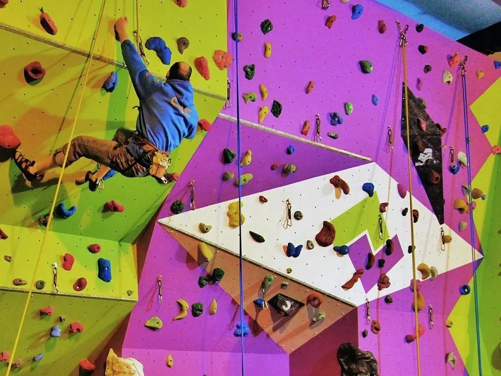 Escalador en una pared de escalada de interior con paneles de colores