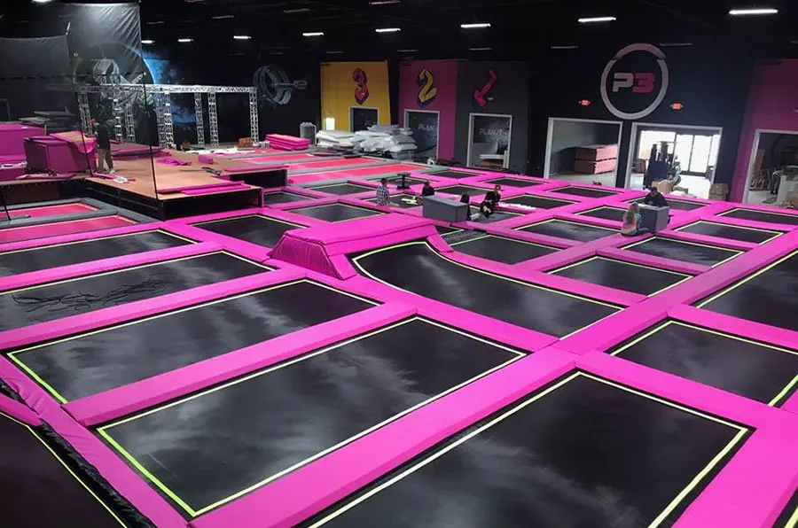 Trampoline park con camas elásticas en cuadrícula y protecciones de color
